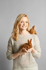 Wall Mural - Beautiful girl with small rabbits on grey background