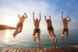 © Song_about_summer - group of friends jumping to the sea from the pier, happy beach holidays