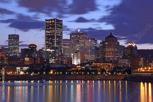 Montreal Downtown Panorama at sunset. Montreal reflected on the river at dusk with city lights and urban buildings. Montreal over river at sunset with city lights. Montreal reflected in water. © romanbarisev