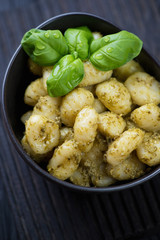 Wall Mural - Potato gnocchi served with pesto sauce in a ceramic bowl and decorated with fresh green basil leaves, close-up