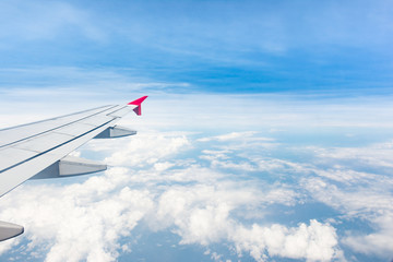 Aerial view of cloud  blue sky and plane wing view through the airplane  window.