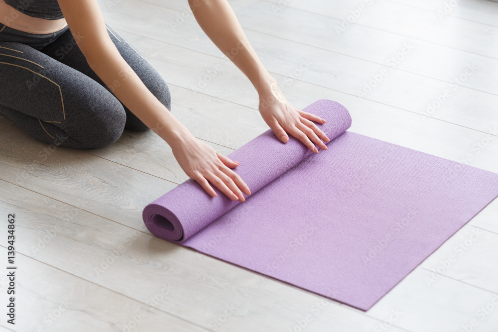 Young yoga Woman rolling her lilac mat - obrazy, fototapety, plakaty 