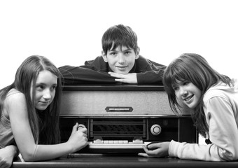 Wall Mural - Teenage boys and girls listening to old vintage radio isolated on white in black and white