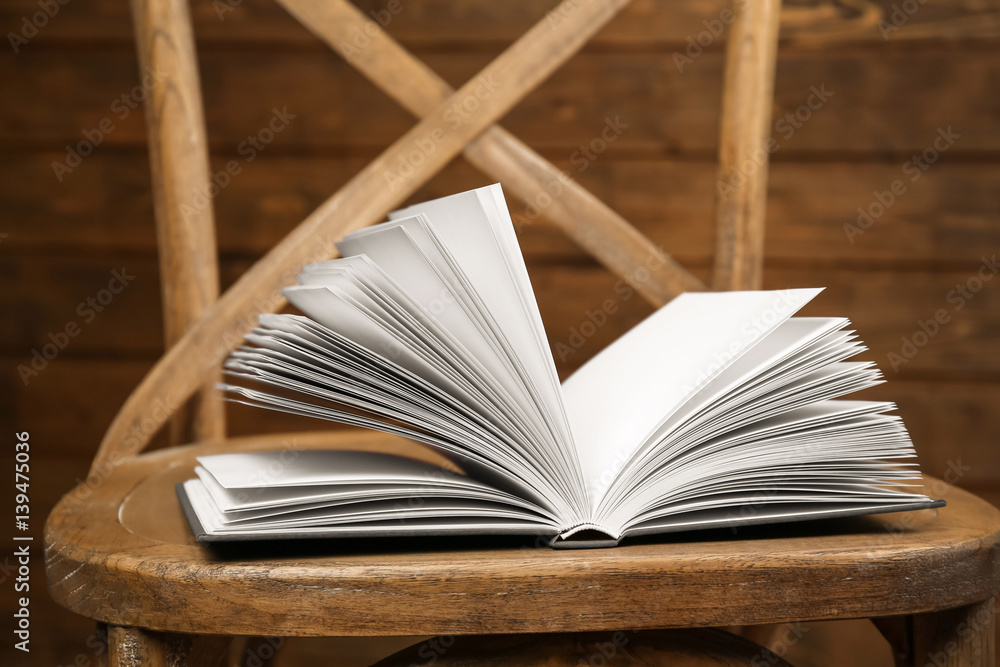 Chair with new book on wooden background