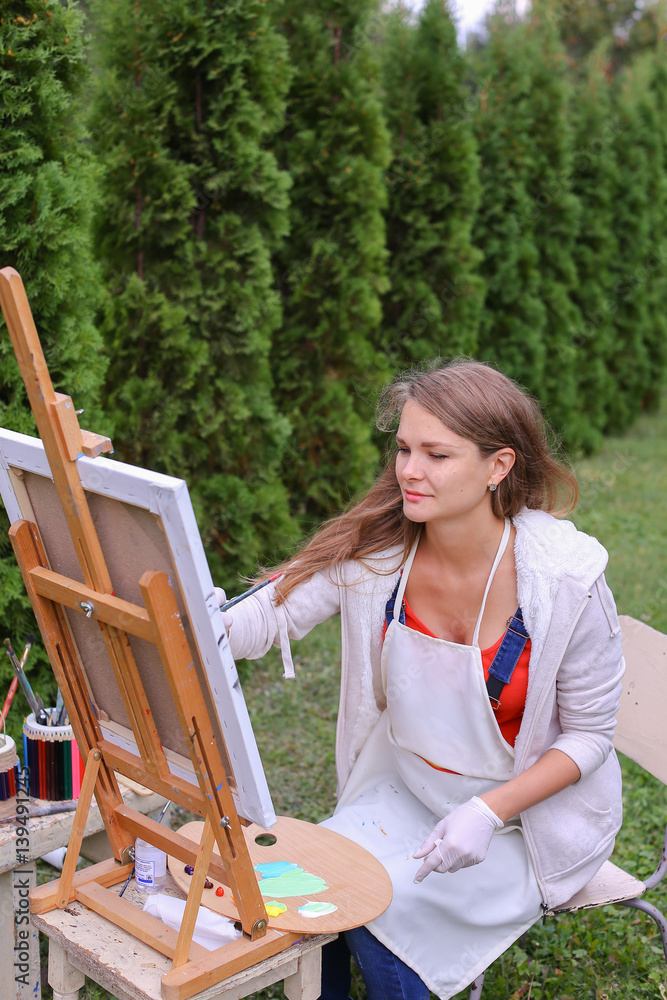 Girl artist paints picture and sits on chair at easel sides of t Stock ...