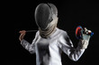 Portrait of fencer woman wearing white fencing costume practicing with the sword. Isolated on black background.