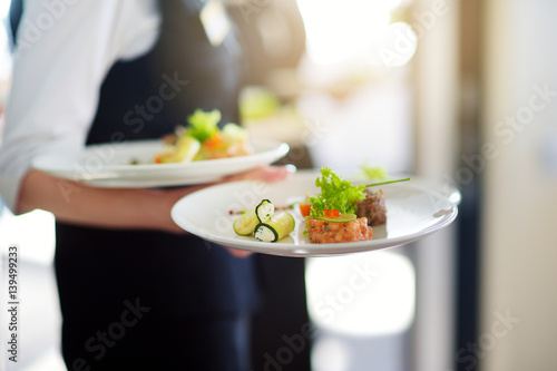 Fotografie, Obraz Waiter carrying plates with meat dish on some festive event