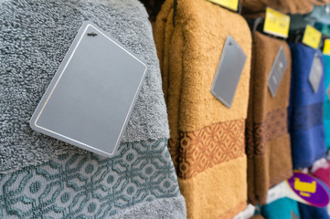 Colorful towels with Blank Label on shelf of rack background