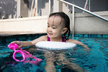 Wall Mural - Asian Chinese little girl playing at the outdoor swimming pool