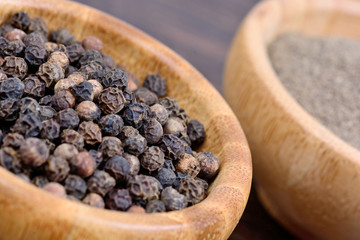 Wall Mural - Black peppercorns and powder in a bamboo bowl