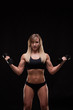 © satyrenko - Beautiful athletic woman pumping muscles with dumbbells, isolated on dark background with copyspace