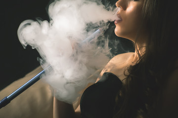 Young, beautiful girl smoke a hookah at club