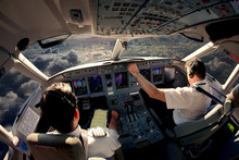 Flight Deck Of Modern Passenger Jet Aircraft. Pilots At Work. Cloudy Sky And Sunset View From The Airplane Cockpit.