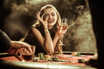 portrait of smiling woman with drink and poker chip playing poker