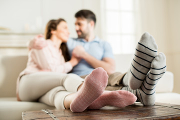 Wall Mural - couple hugging on sofa at home, focus on foreground