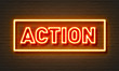 Action neon sign on brick wall background.