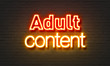 Adult content neon sign on brick wall background.
