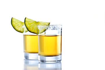 Shot of golden tequila with lime on a white background for isolation