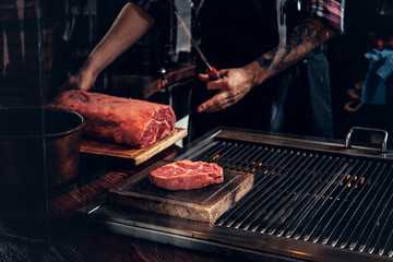 A man cooking beef steak on a grill.