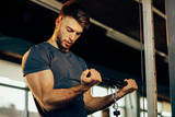 Handsome man doing heavy weight exercise for biceps in the gym