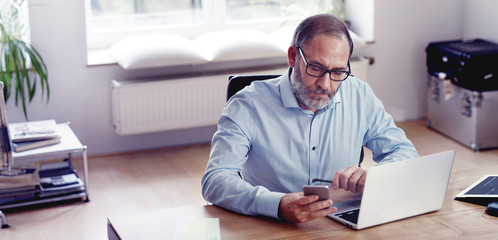 Grey Bearded mature man creative director sitting in modern office