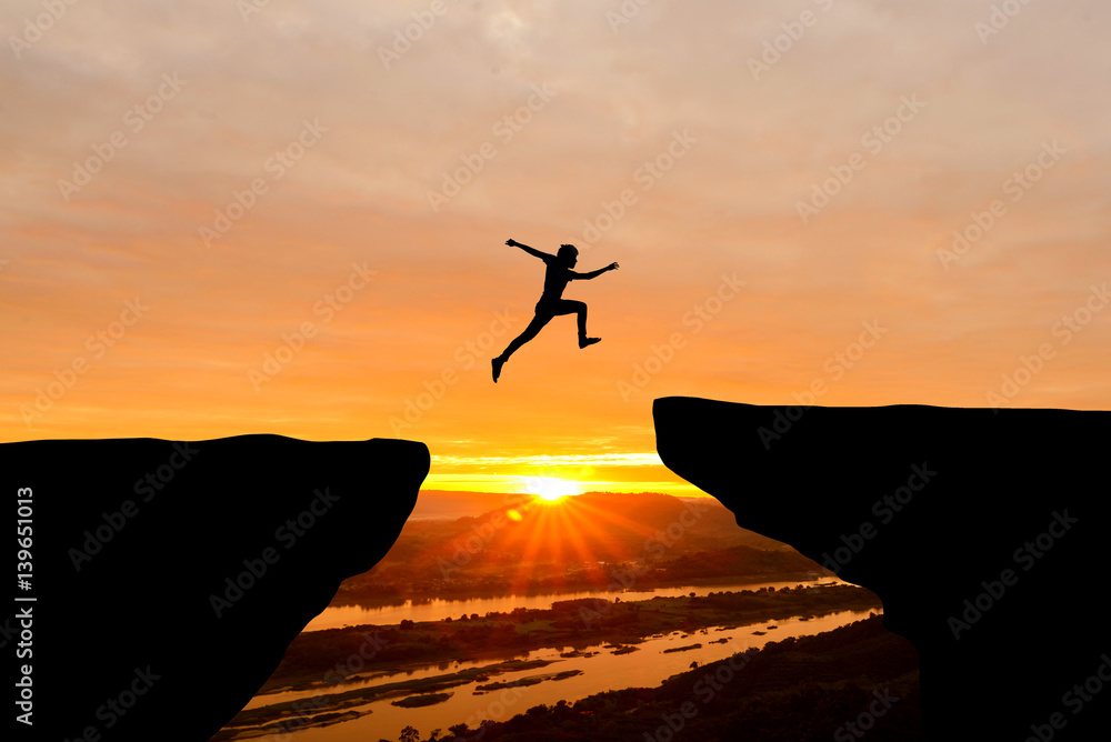 Courage man jumping over cliff on sunset background,Business concept idea - obrazy, fototapety, plakaty 