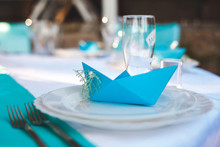 The Table In The Restaurant For A Wedding In A Marine Style. Guest Card In A Paper Boat Blue