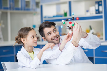 Wall Mural - Smiling teacher and student scientists looking at molecule model in lab