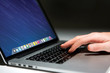 © Production Perig - Hand typing on a keyboard of laptop with operating system screen on background