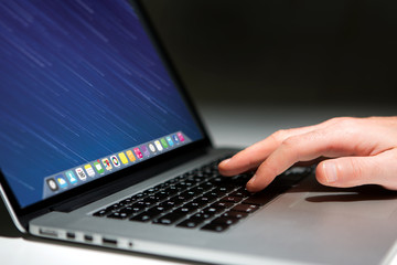 Hand typing on a keyboard of laptop with operating system screen on background
