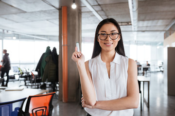 Smiling young businesswoman standing and holding whiteboard merker in office