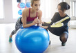 © gpointstudio - Instructor helping woman balancing on fitness ball