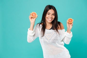 Smiling attractive young woman holding two halves of grapefruit