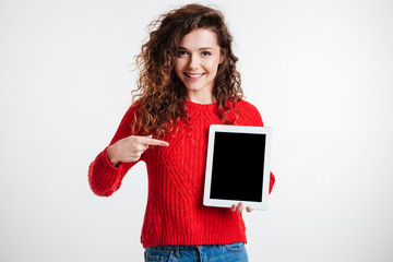 cheerful cute woman pointing finger on blank screen tablet