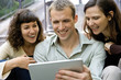 © PhotoAlto - Friends using digital tablet outdoors