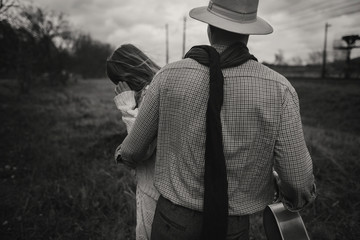 Wall Mural - boho gypsy woman and man in hat embracing in windy field.stylish hipster couple dancing. atmospheric motion moment. fashionable look. rustic wedding concept. black white photo