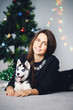 © Parilov - Girl on the background of a Christmas tree with a puppy of a husky. Dog black and white with blue eyes. Concept gift for the new year dog.