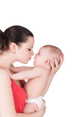 loving mother tries to kiss her cute baby. surprised child looks at mother, isolated on white