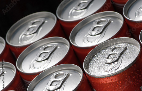 Fotomural Un grupo de latas de lata roja con gotas de agua de cerca sobre un fondo negro