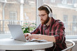 © Drobot Dean - Handsome serious bearded young man using laptop and listening music.