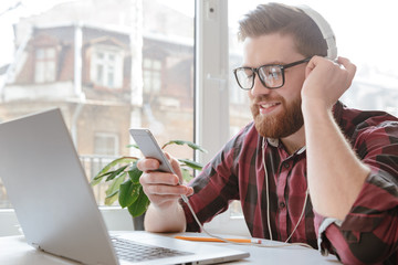 Poster - Bearded happy young man using phone and listening music.