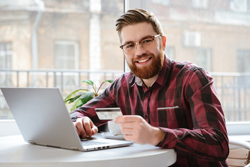 Poster - Bearded young man holding debit card.