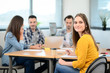 © W PRODUCTION - portrait of young woman in casual wear working in a creative business startup company office with coworker people in background