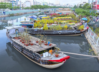 Wall Mural - Ho Chi Minh City, Vietnam - January 26, 2017: Flowers boats at flower market on along canal wharf. This is place where farmers sell apricot blossom and other flowers on Lunar New Year in Vietnam