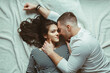 © anoushkatoronto - Portrait of beautiful romantic young couple man woman in love hugging, kissing, lying on floor on white rug carpet indoors at home, toned with filters, view from top above, authentic lifestyle