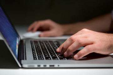 Hand typing on a keyboard of laptop with operating system screen on background