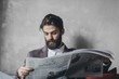 © LUMINA IMAGES - Handosme businessman with beard reading newspapers at cafe.