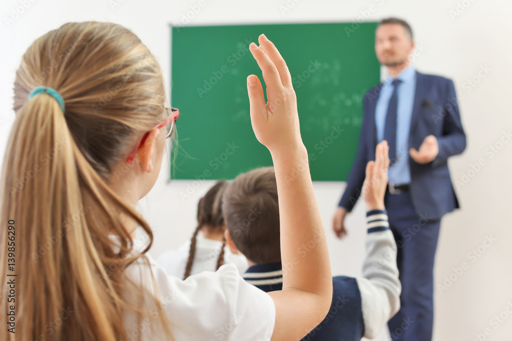 Schoolgirl raising hand for answer during lesson