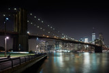 Fototapeta Miasta - Brooklyn Bridge and New York city skyline illuminated at night with docks