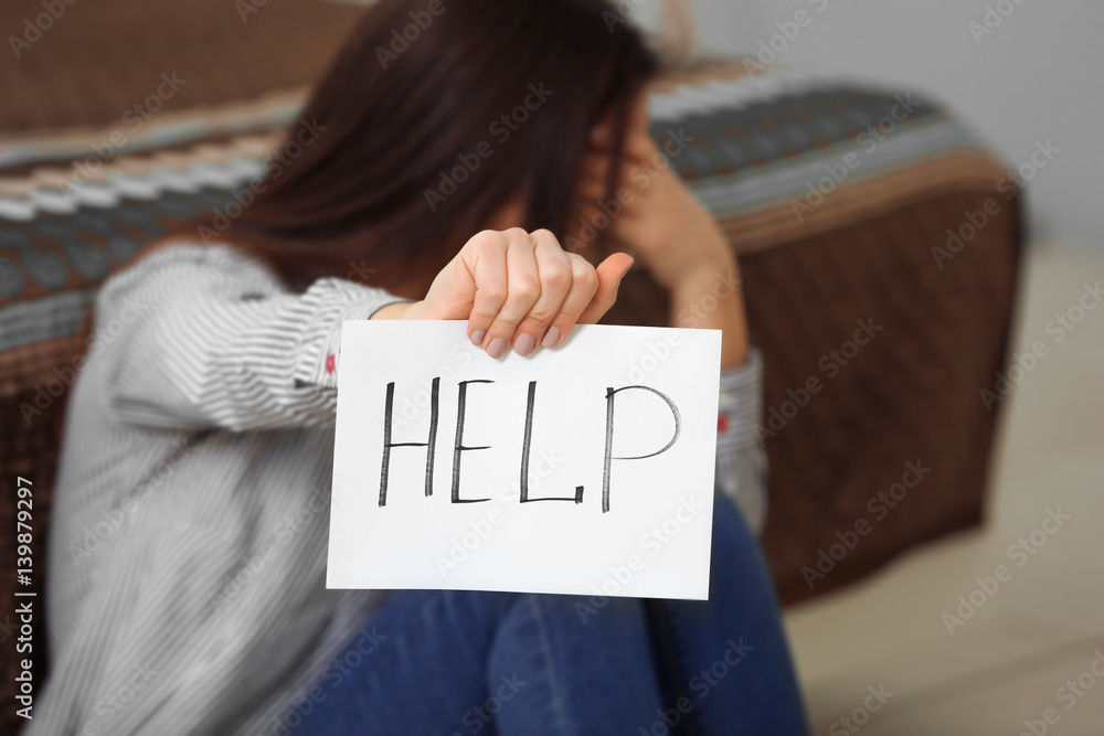 Woman holding sheet of paper with word HELP